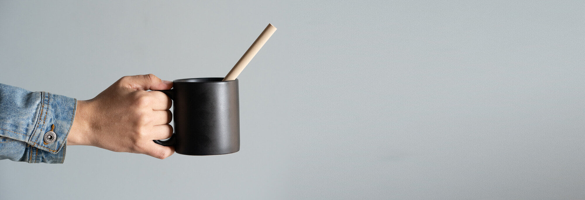 Hand holding a cup with a bamboo straw