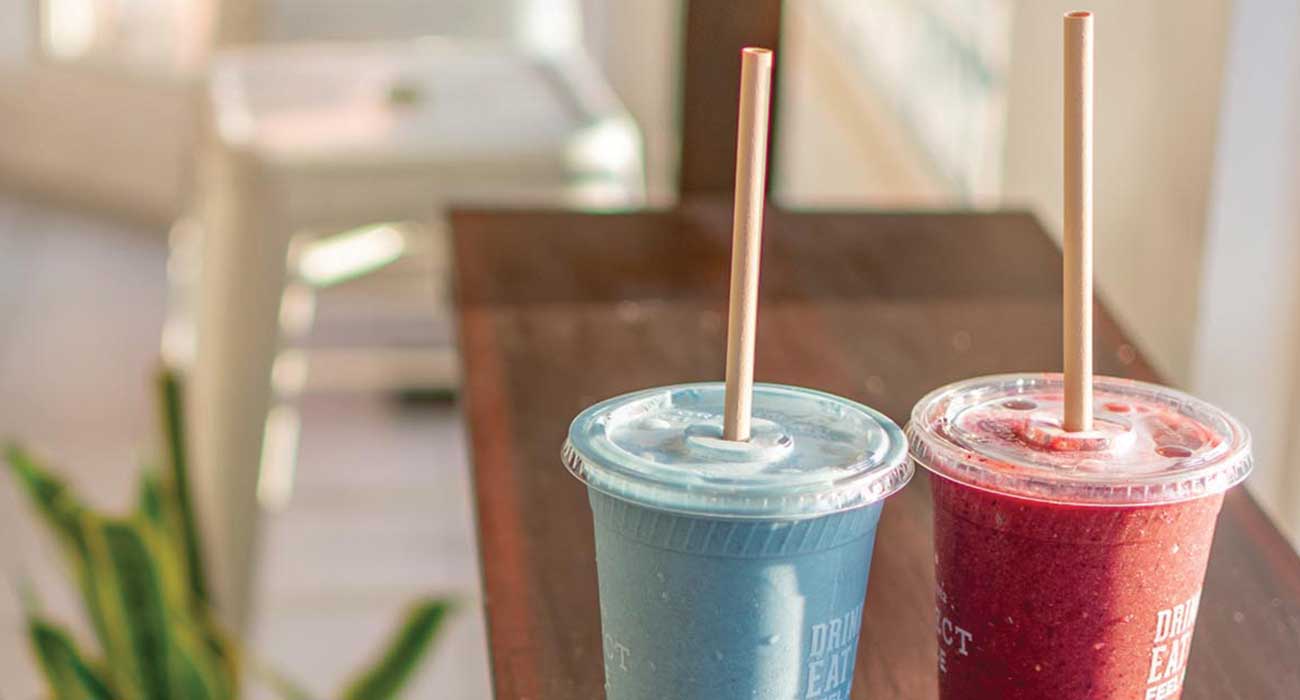 Two regular straws in a blue shake and a red drink.